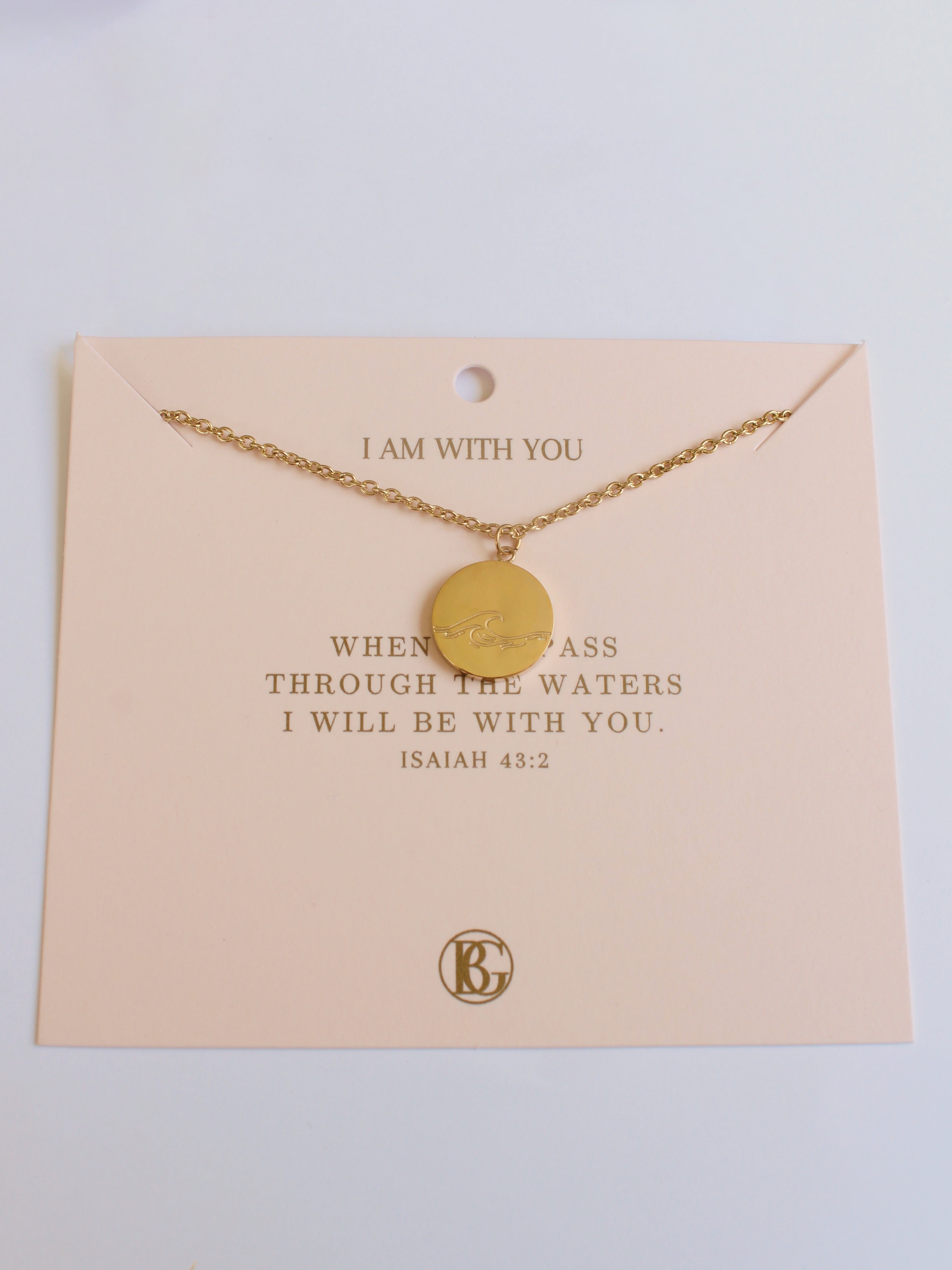 Gold necklace on a beige card with text and a logo