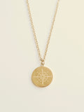 Gold necklace with a compass pendant on a beige background