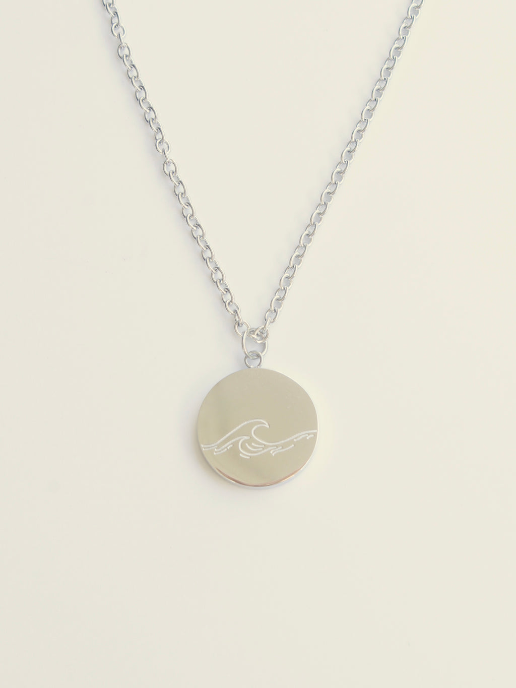 Necklace with a round pendant featuring a wave design on a beige background